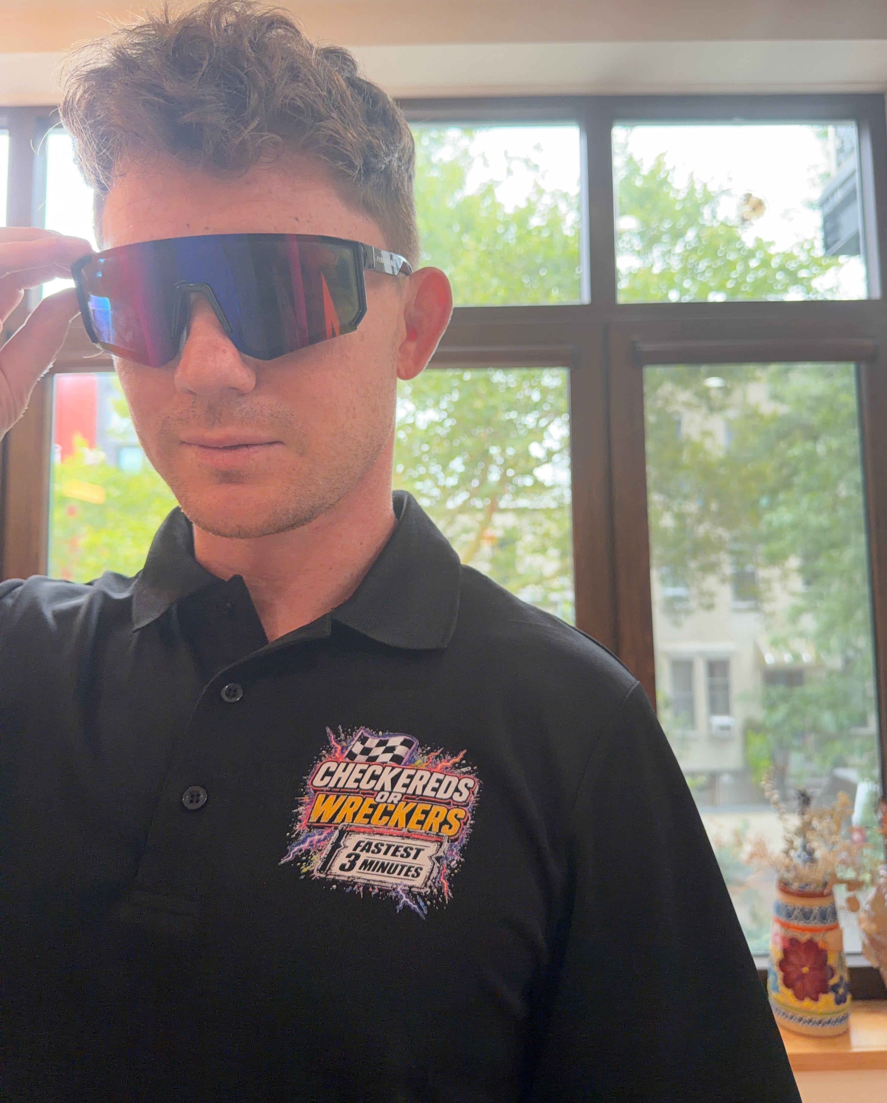 Checkereds or Wreckers black polo adjusting sunglasses chest logo close-up